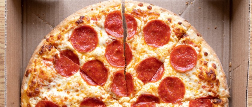 Half of a pepperoni pizza in takeout box